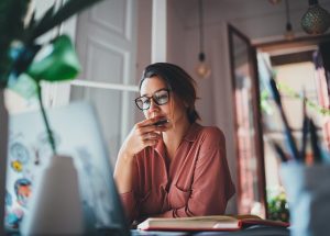 Woman sitting in front of the computer while thinking